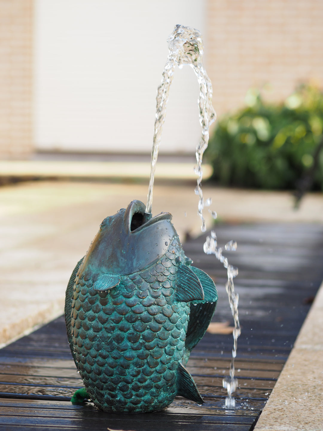 Bronze fountain sculpture of a fish spraying water upwards