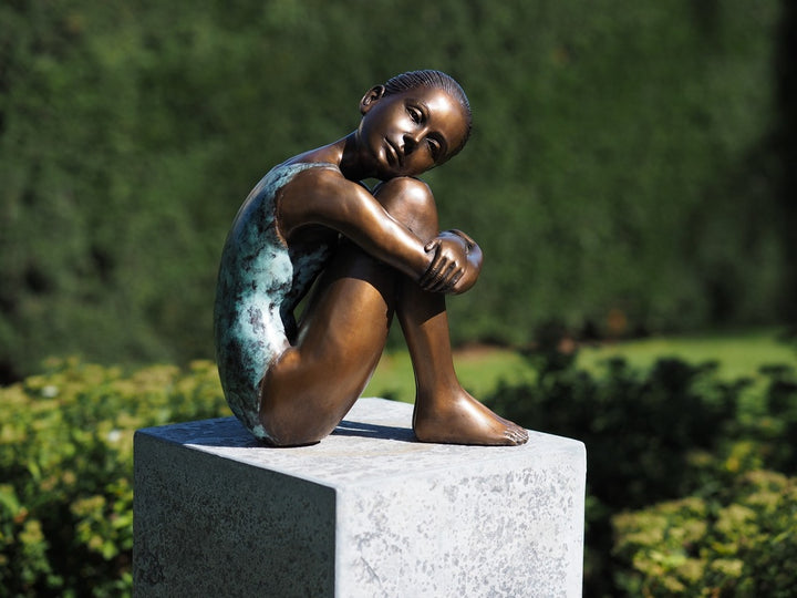 Bronze sculpture of a young girl in swimsuit resting her head