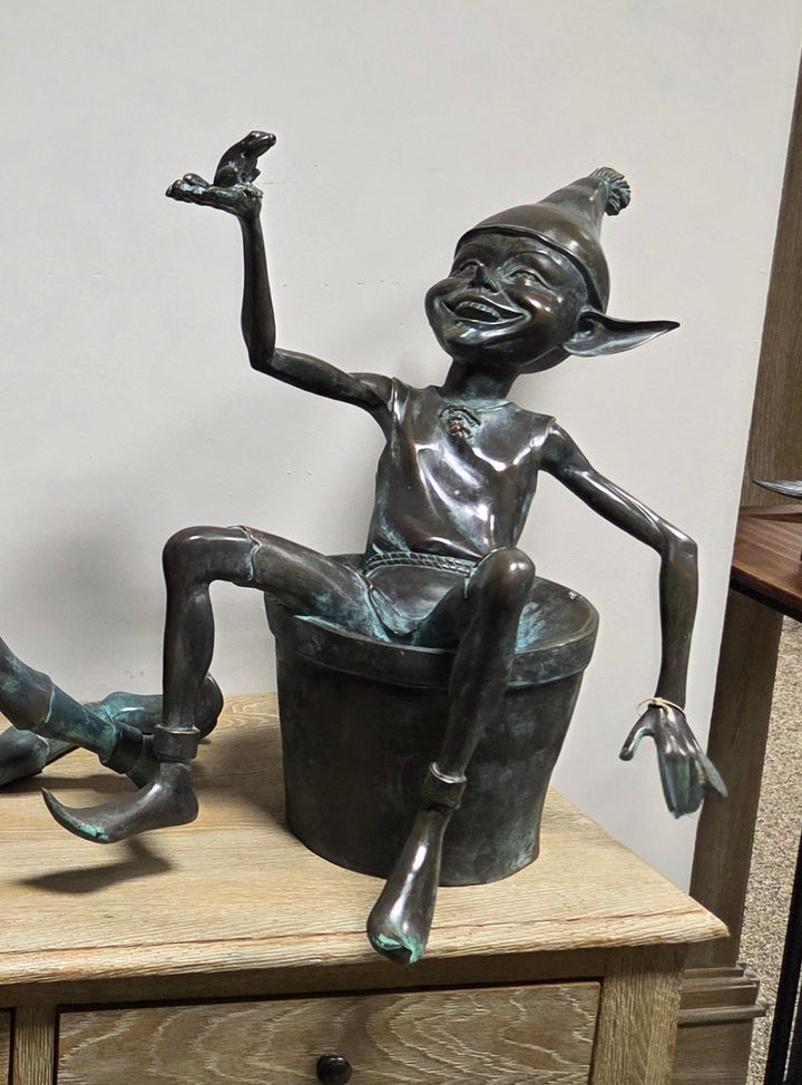 Bronze sculpture of a pixie with a frog sitting in a bucket
