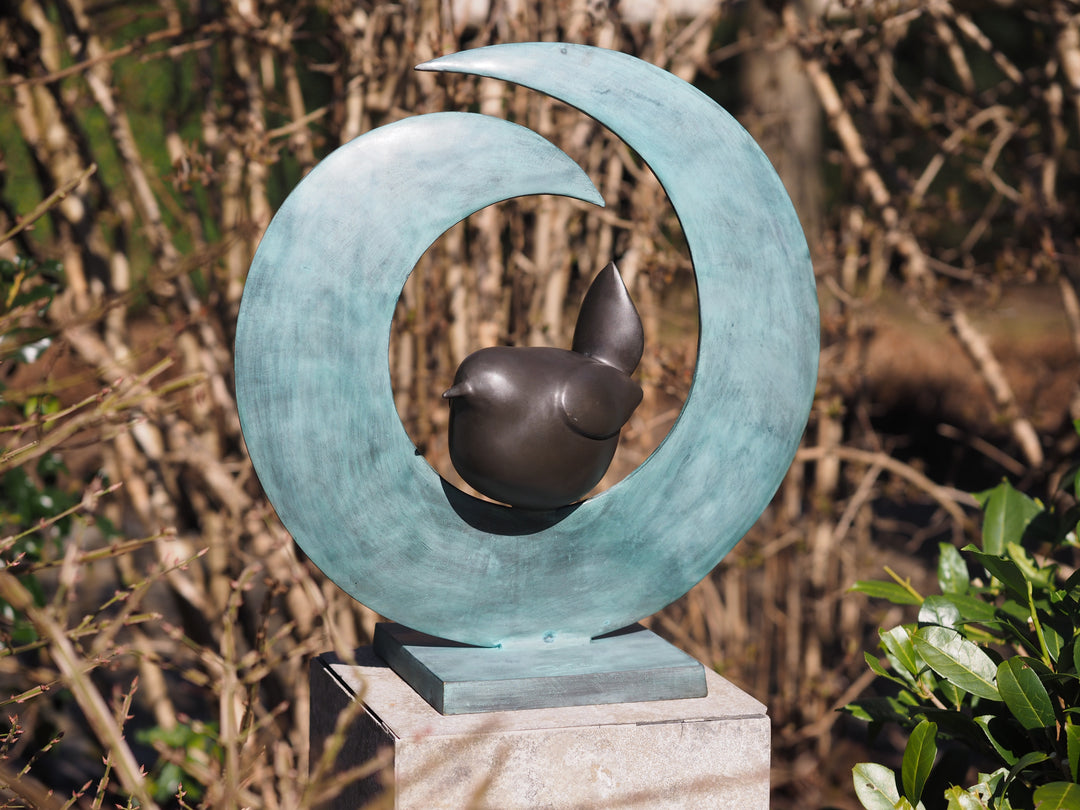 Modern bronze sculpture of a bird sitting in a crescent form