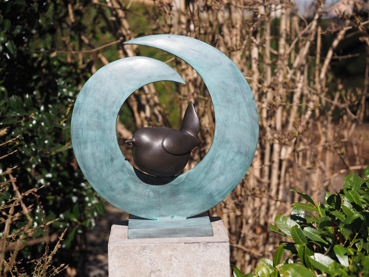 Modern bronze sculpture of a bird sitting in a crescent form