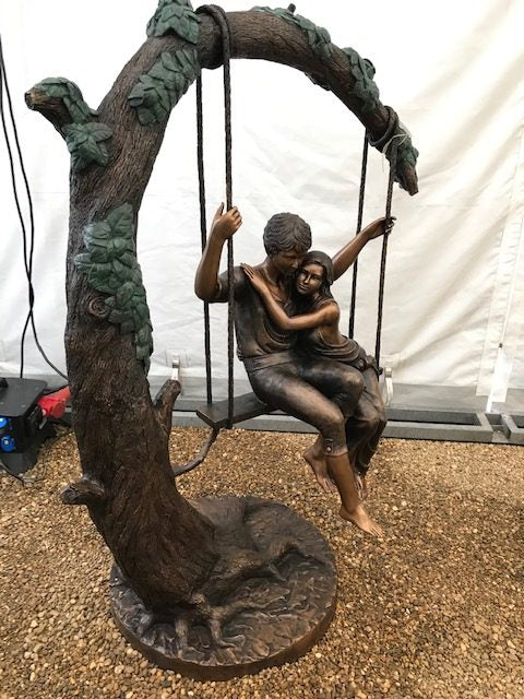 Large bronze sculpture of a young couple on a swing