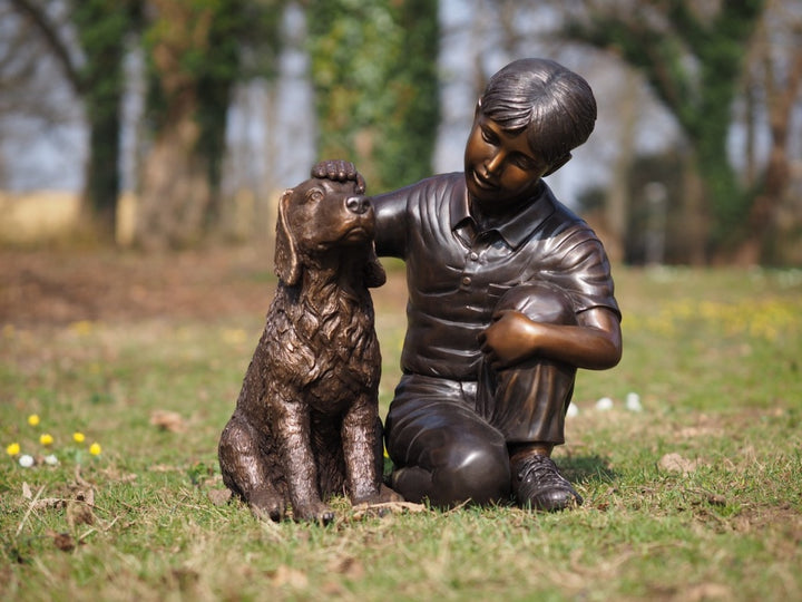 Bronze sculpture of a young boy petting his dog
