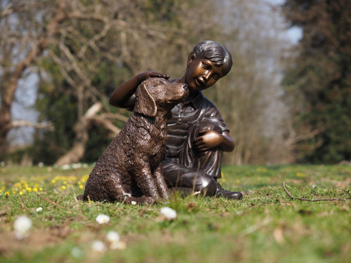 Bronze sculpture of a young boy petting his dog