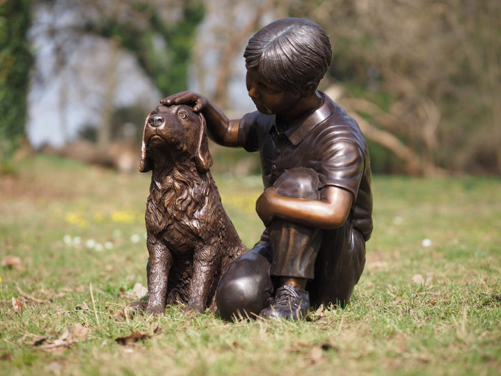 Bronze sculpture of a young boy petting his dog