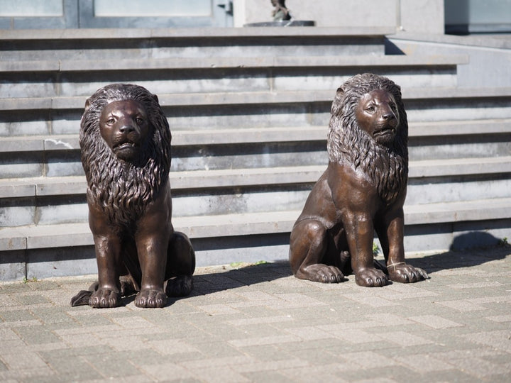 Pair of bronze sitting lion sculptures