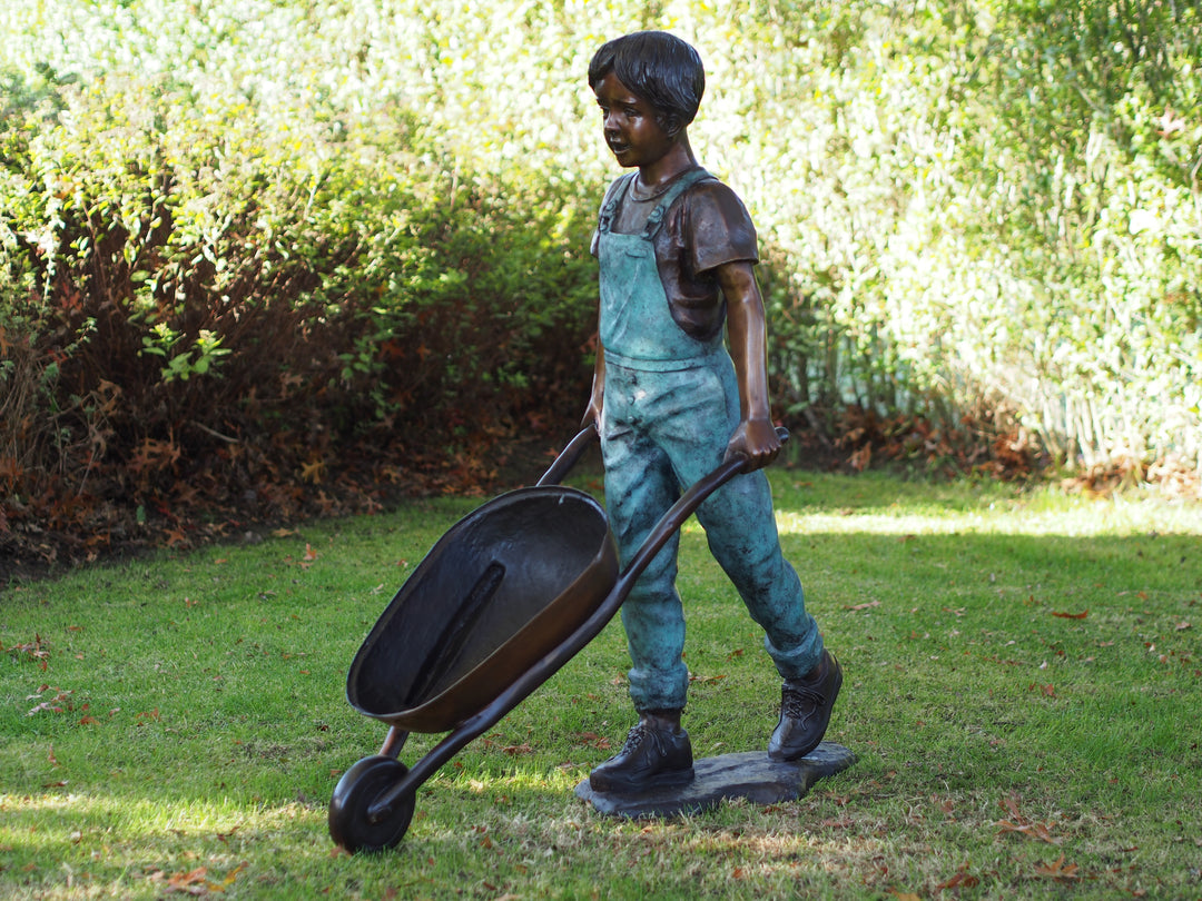 Large bronze sculpture of a young boy with a wheelbarrow