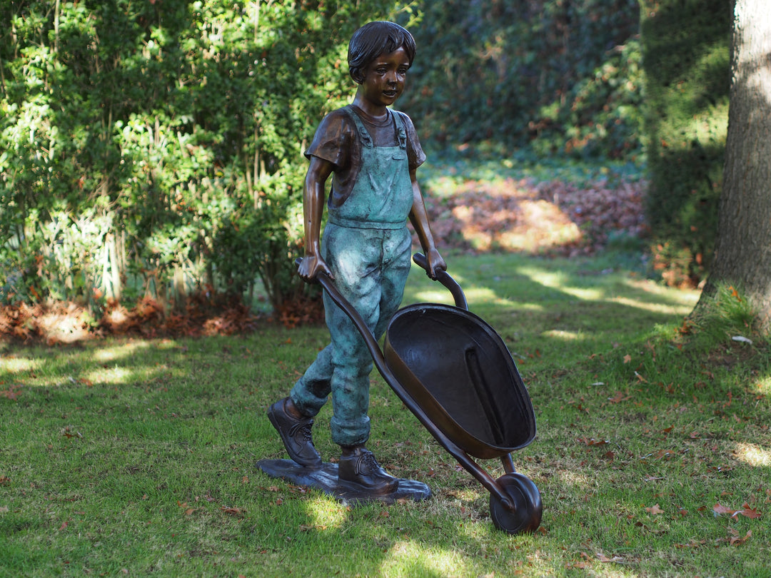 Large bronze sculpture of a young boy with a wheelbarrow