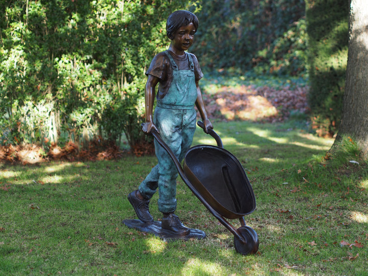 Large bronze sculpture of a young boy with a wheelbarrow