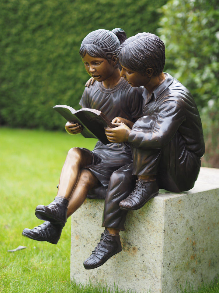 Bronze sculpture of a sitting boy and girl reading