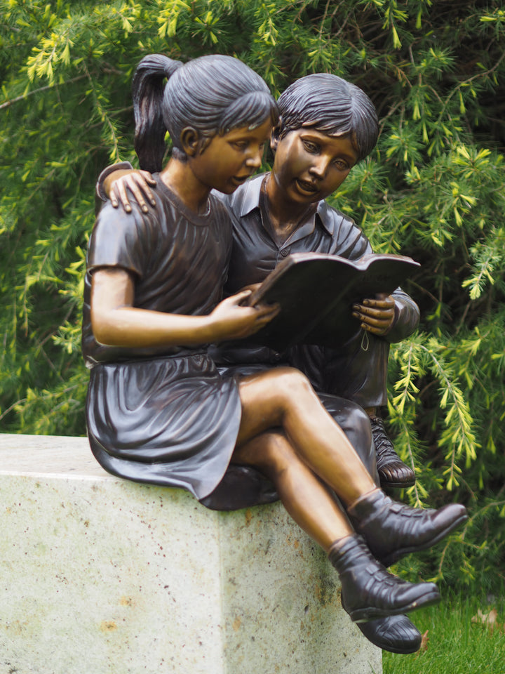 Bronze sculpture of a sitting boy and girl reading