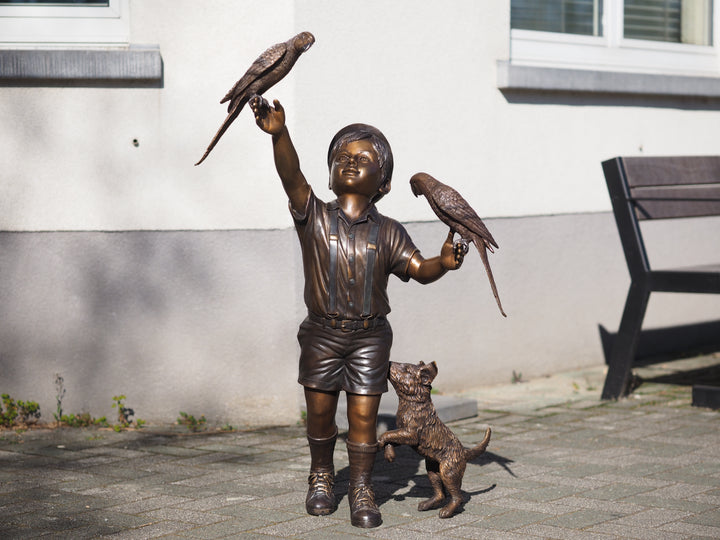Bronze sculpture of a boy with parakeets and dog
