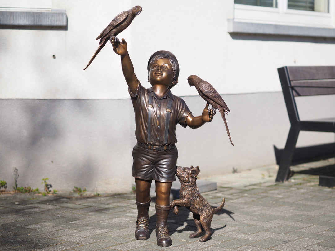 Bronze sculpture of a boy with parakeets and dog