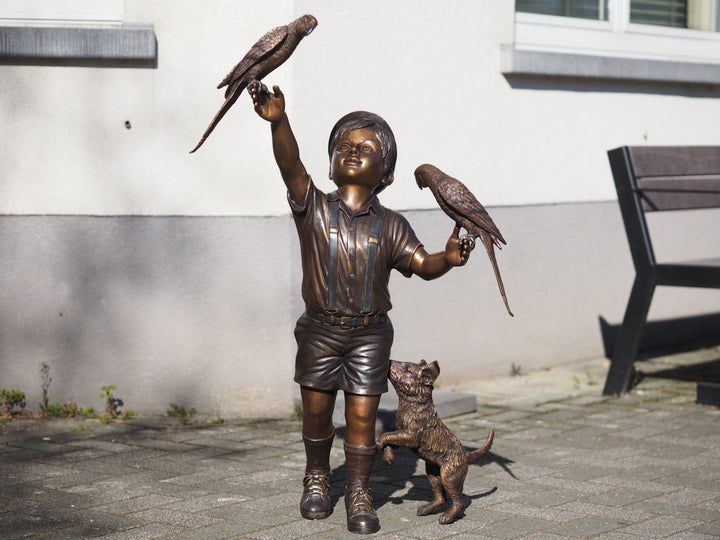 Bronze sculpture of a boy with parakeets and dog