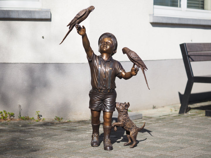 Bronze sculpture of a boy with parakeets and dog
