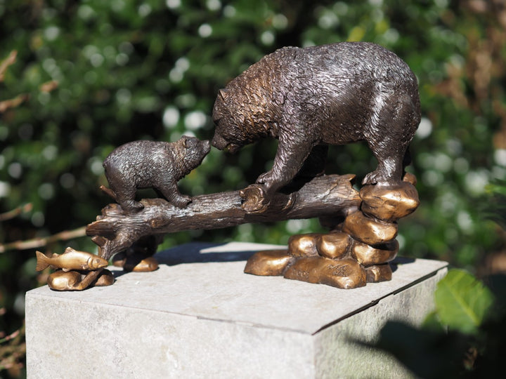 Bronze sculpture of a bear with cub on tree trunk