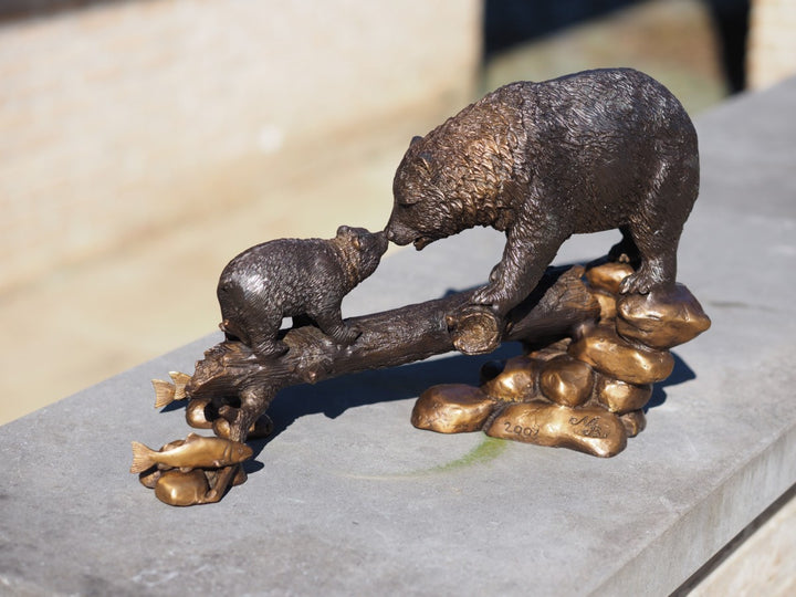 Bronze sculpture of a bear with cub on tree trunk