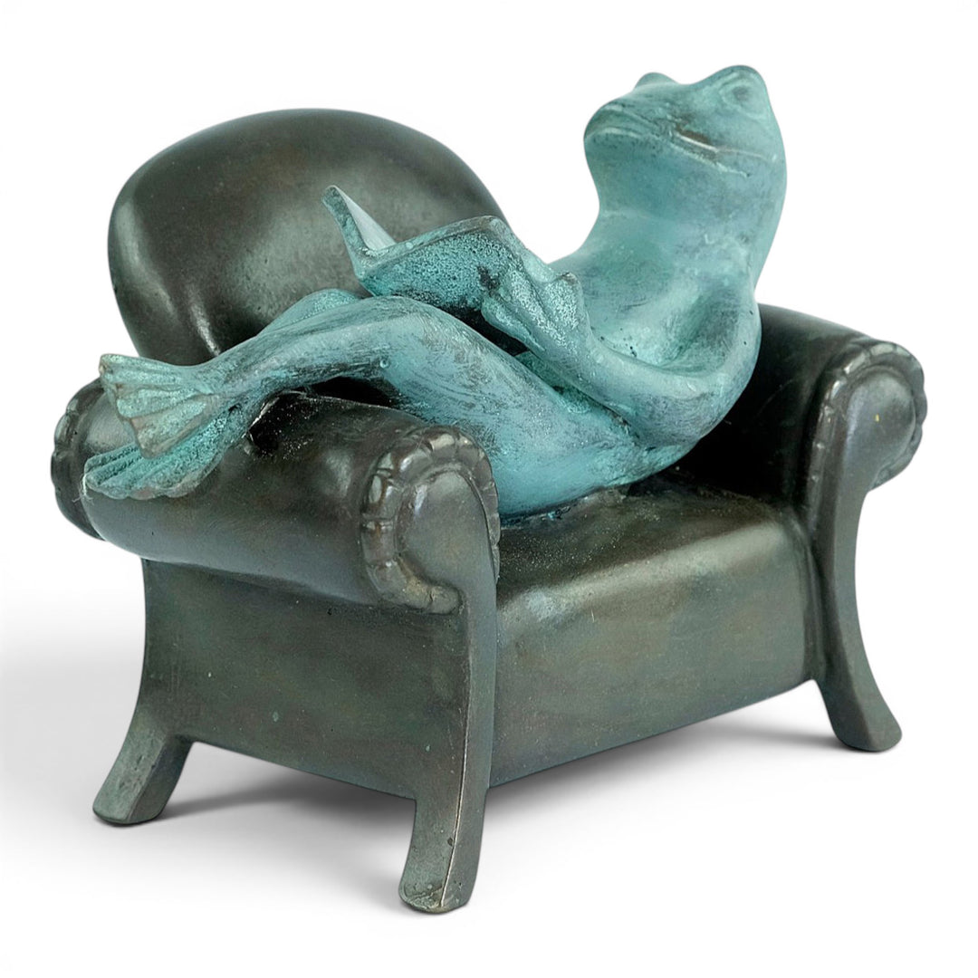 Escultura de bronce de una rana leyendo en un sillón