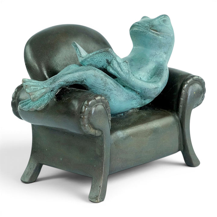 Escultura de bronce de una rana leyendo en un sillón