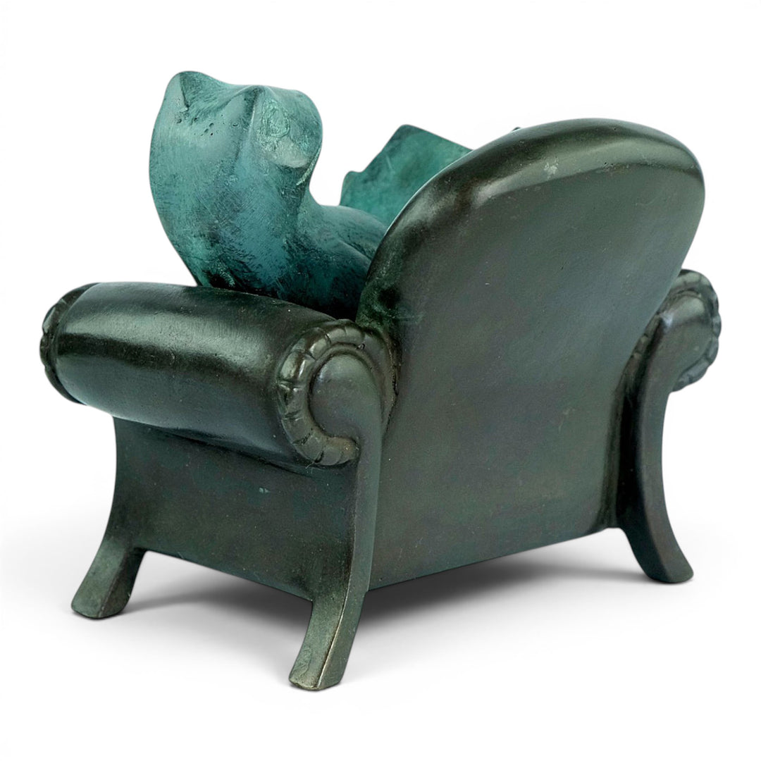 Escultura de bronce de una rana leyendo en un sillón