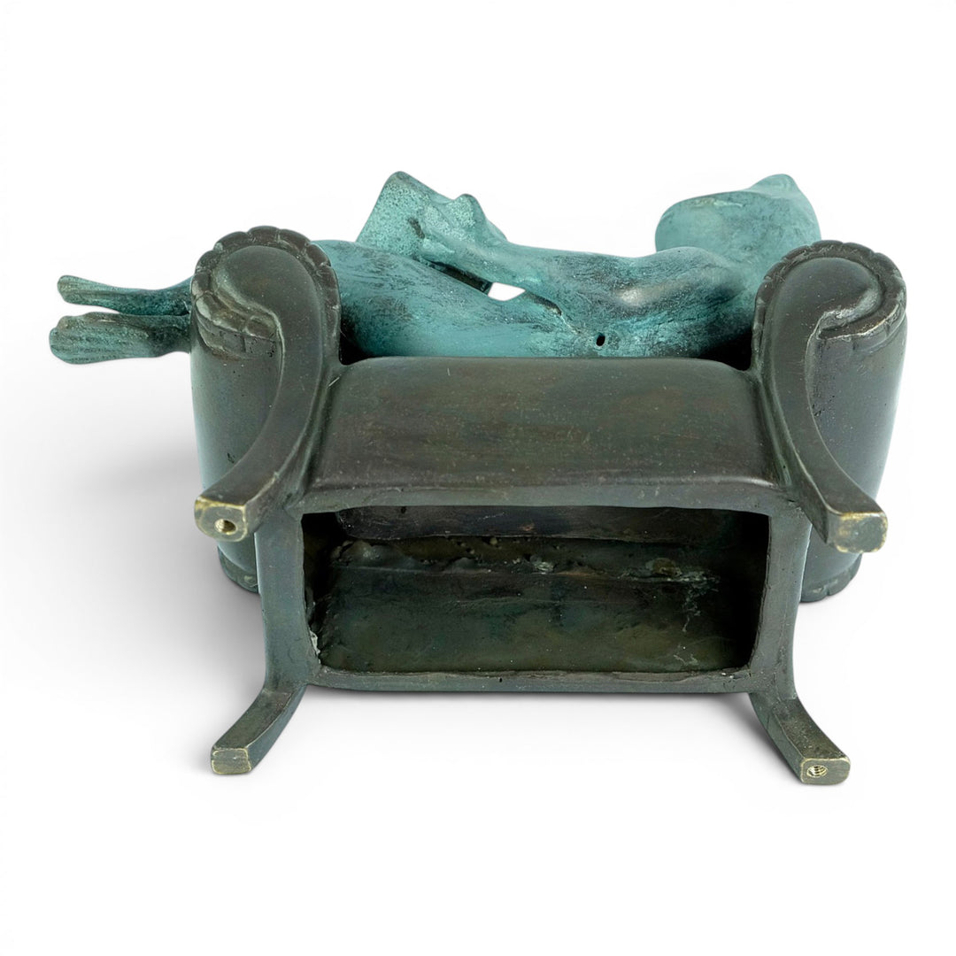 Escultura de bronce de una rana leyendo en un sillón