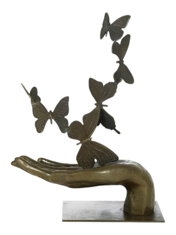Modern bronzen beeld van een hand die vlinders loslaat