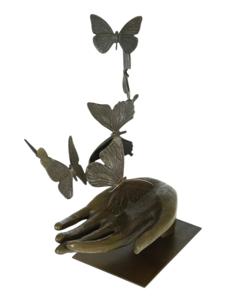 Modern bronzen beeld van een hand die vlinders loslaat
