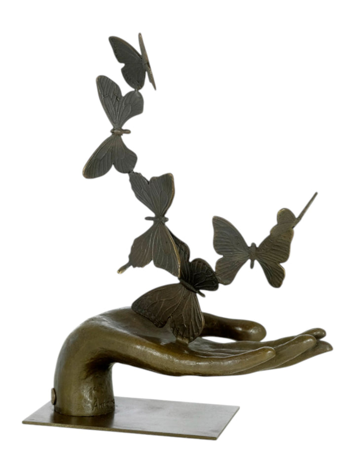 Modern bronzen beeld van een hand die vlinders loslaat