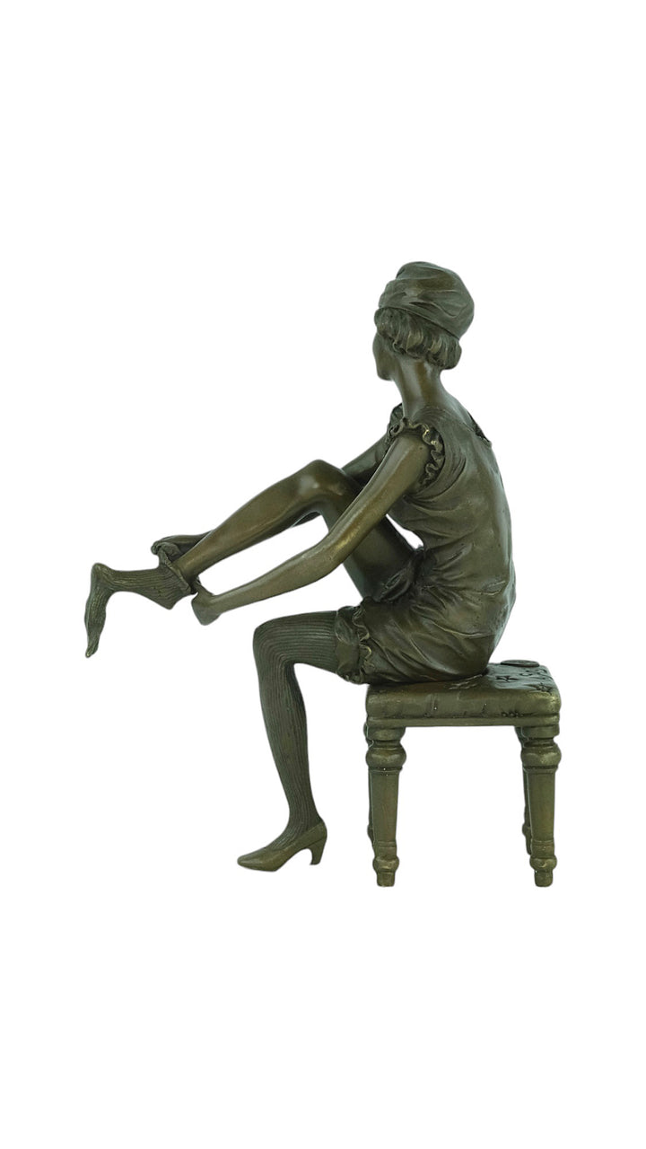 Bronze sculpture of a sitting female putting on stockings