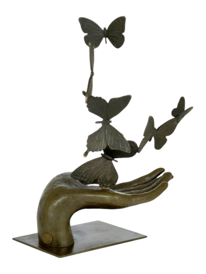 Modern bronzen beeld van een hand die vlinders loslaat