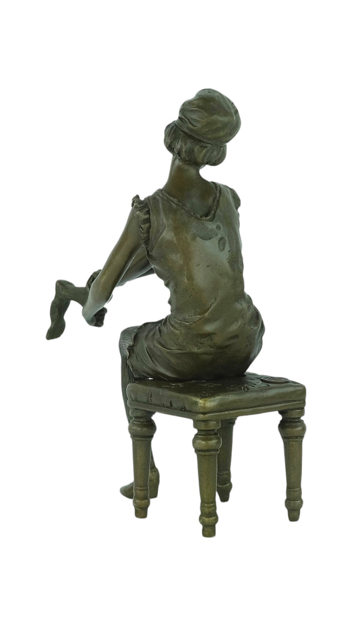 Bronze sculpture of a sitting female putting on stockings