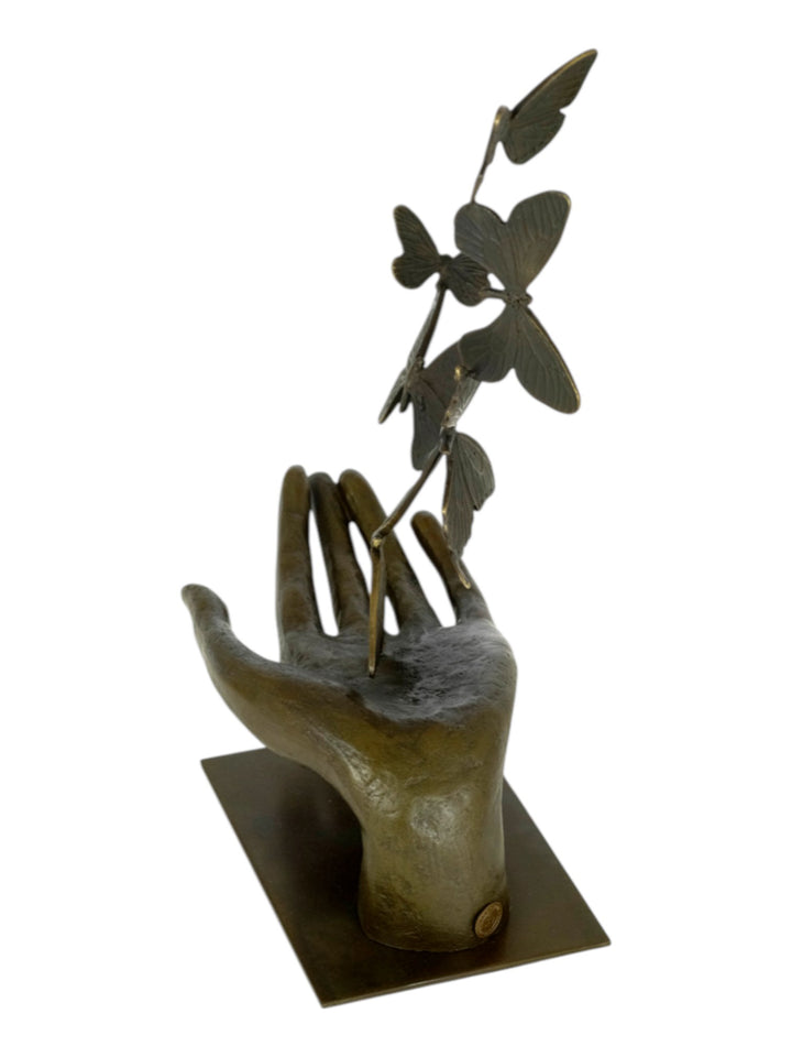 Modern bronzen beeld van een hand die vlinders loslaat