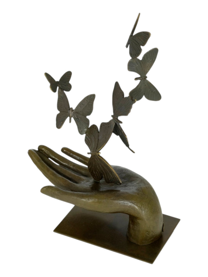 Modern bronzen beeld van een hand die vlinders loslaat