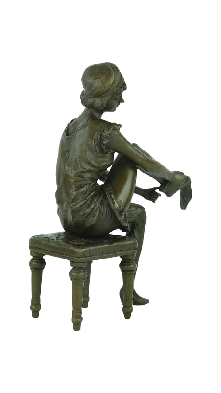 Bronze sculpture of a sitting female putting on stockings