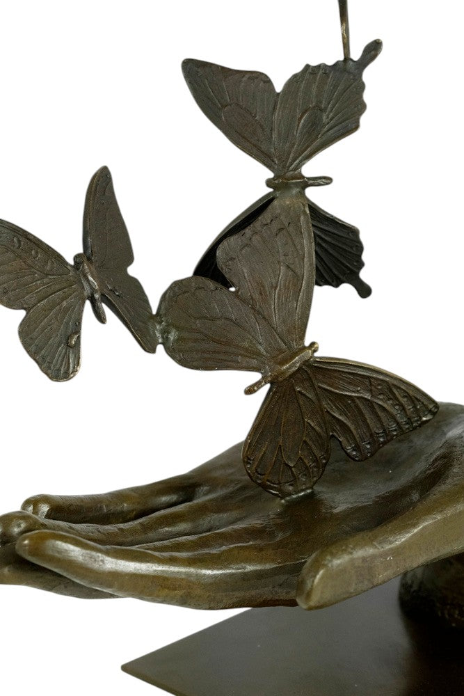 Modern bronzen beeld van een hand die vlinders loslaat