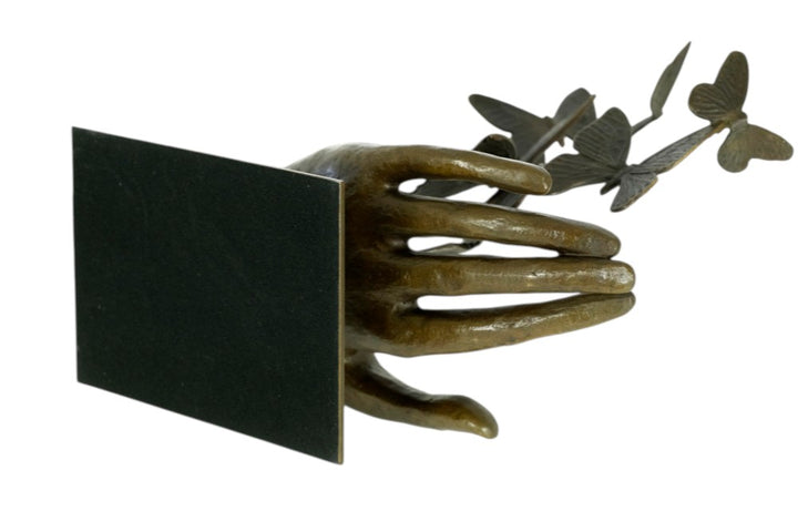 Modern bronzen beeld van een hand die vlinders loslaat