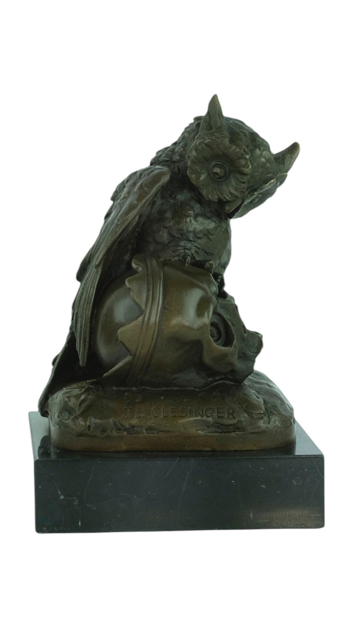 Bronze sculpture of an owl sitting next to a crowned skull