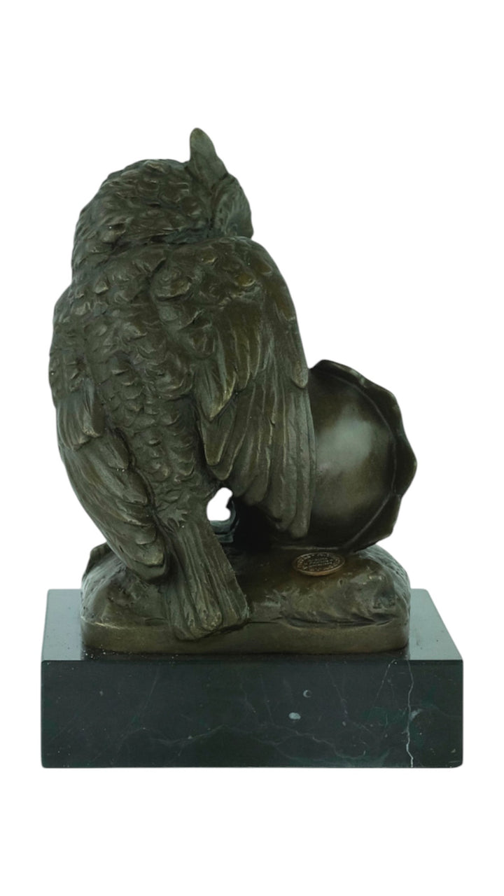 Bronze sculpture of an owl sitting next to a crowned skull