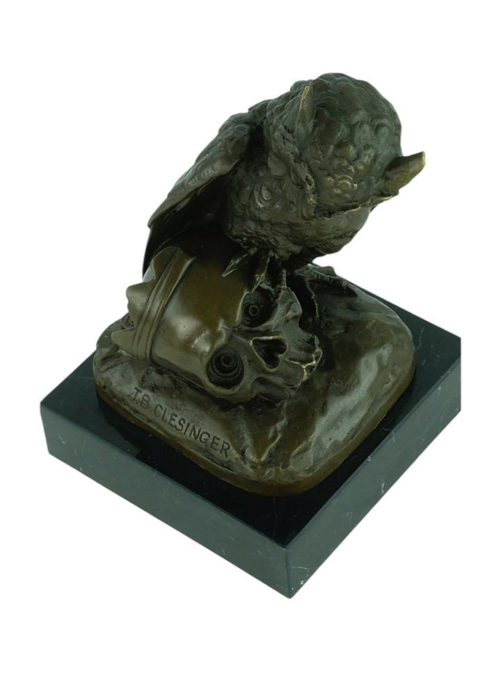 Bronze sculpture of an owl sitting next to a crowned skull