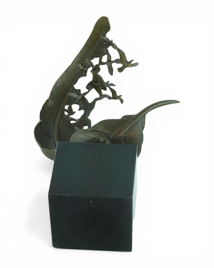 Escultura de bronce de palomas volando de una pluma