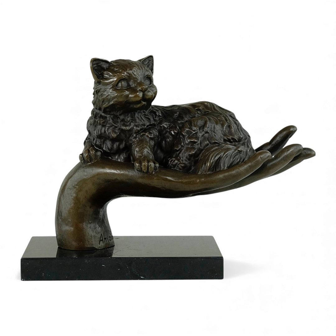 Escultura de bronce de un gato descansando en una mano
