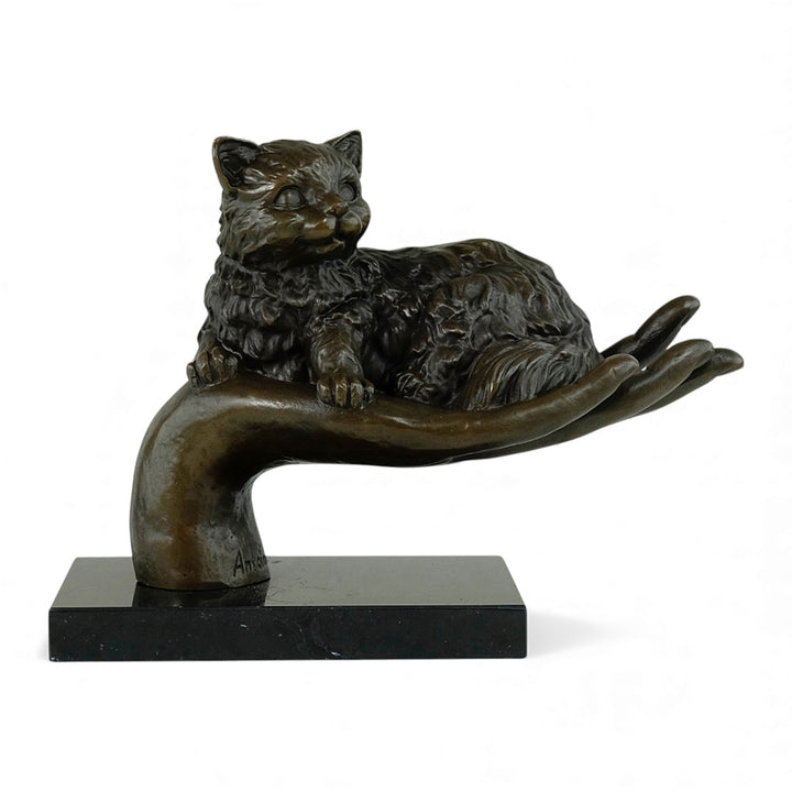 Escultura de bronce de un gato descansando en una mano