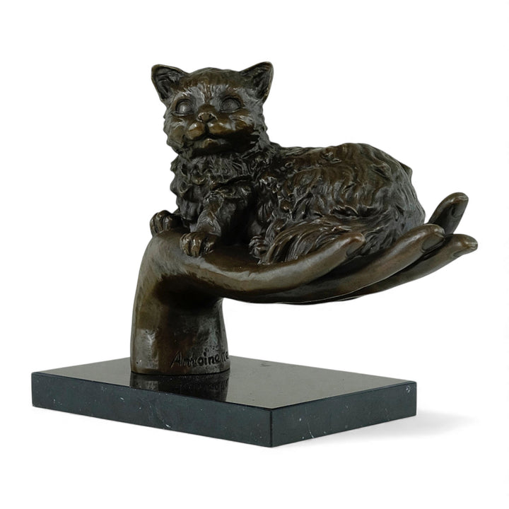 Escultura de bronce de un gato descansando en una mano
