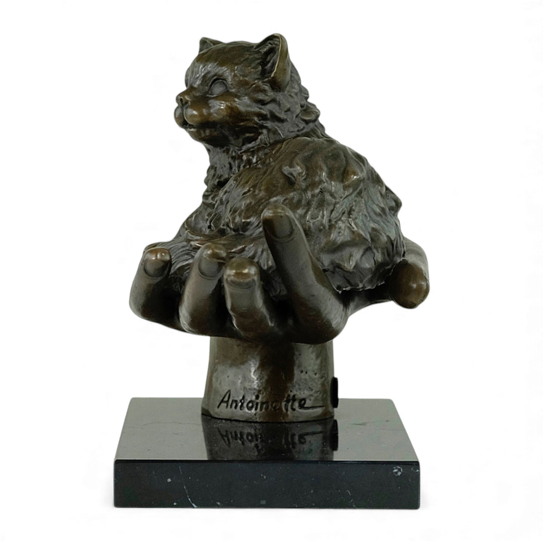 Escultura de bronce de un gato descansando en una mano