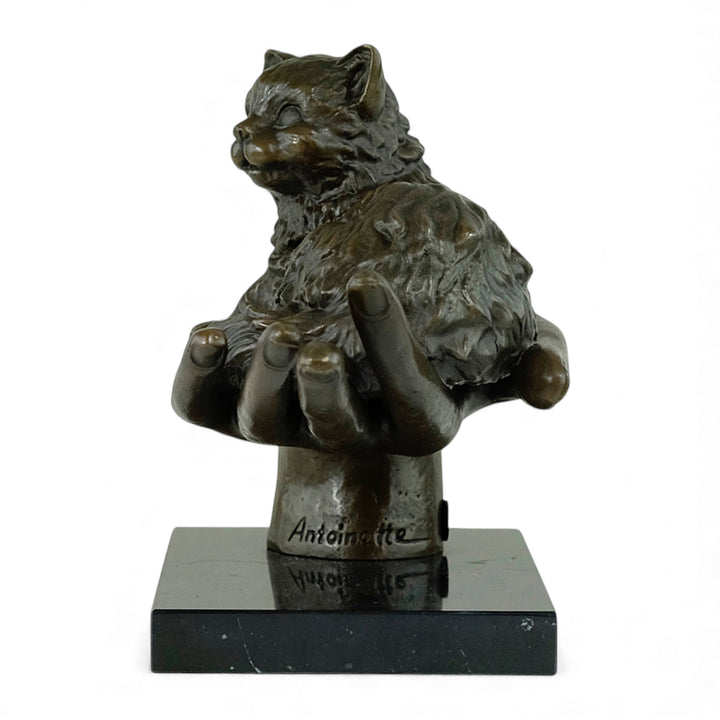 Escultura de bronce de un gato descansando en una mano