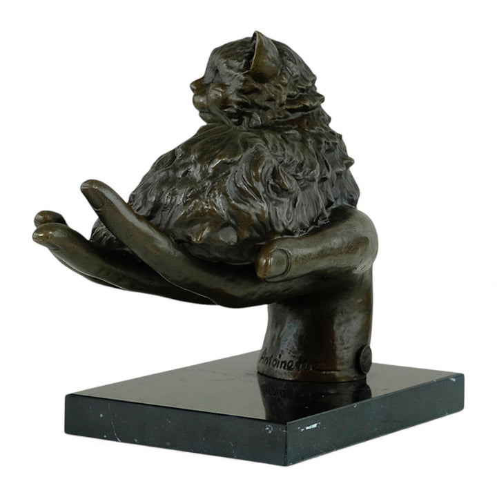 Escultura de bronce de un gato descansando en una mano