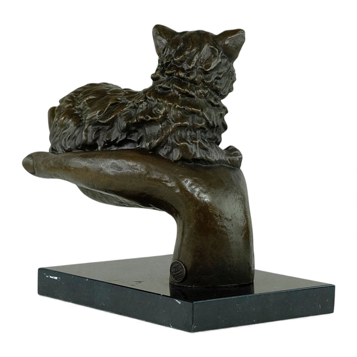 Escultura de bronce de un gato descansando en una mano