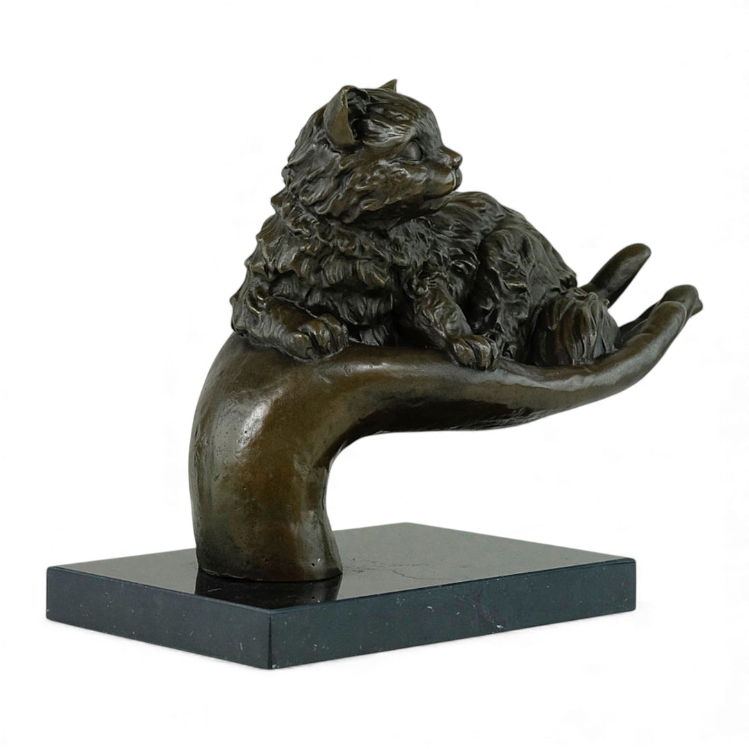 Escultura de bronce de un gato descansando en una mano