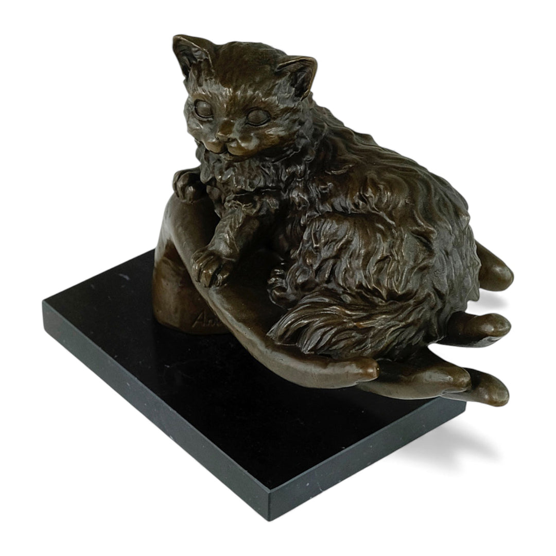 Escultura de bronce de un gato descansando en una mano