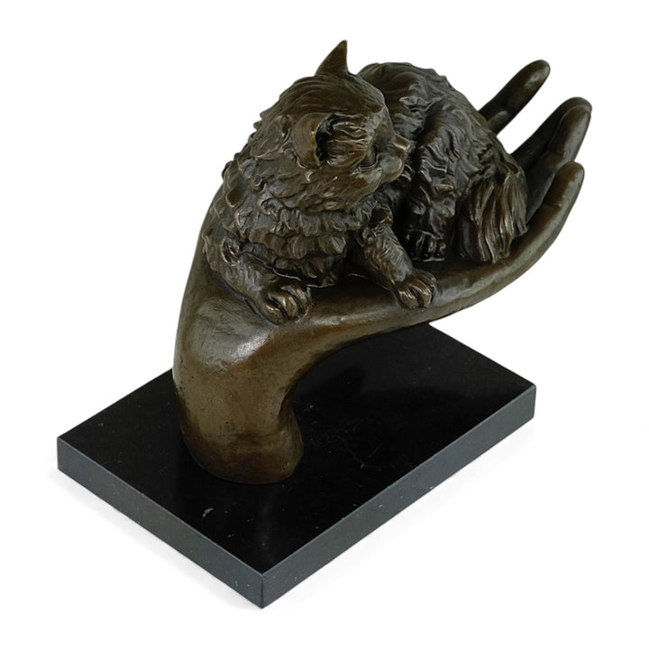 Escultura de bronce de un gato descansando en una mano